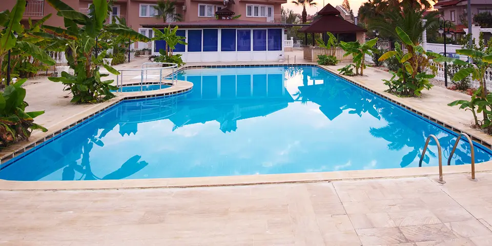 Swimming pool surrounded by tropical plants and a deck, showcasing the potential for resurfacing services by Classic Marcite in Jacksonville Beach.