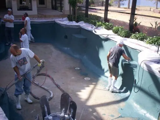 Crew preparing and resurfacing the walls of a drained pool