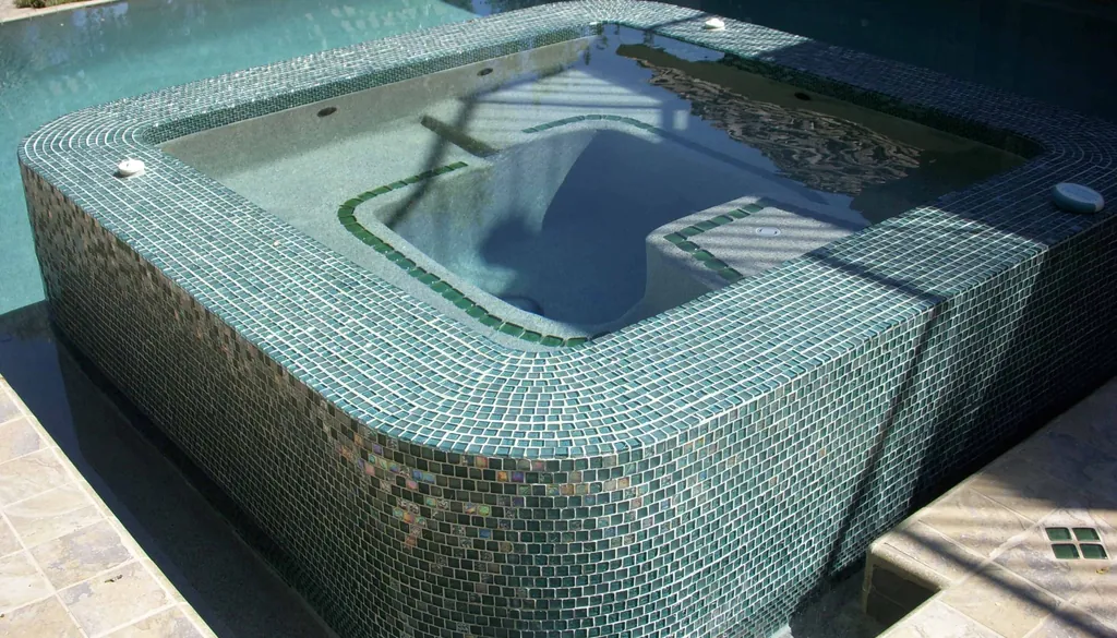 Raised spa covered in iridescent green glass tile