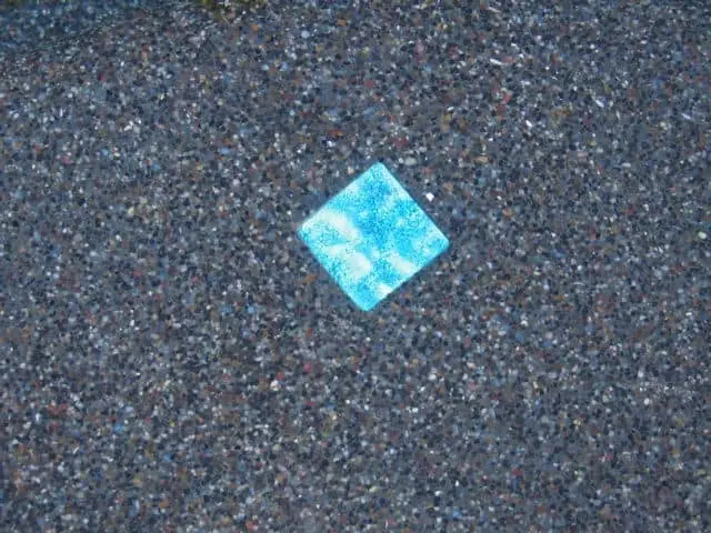 Close-up of a pebble pool finish with a blue accent tile