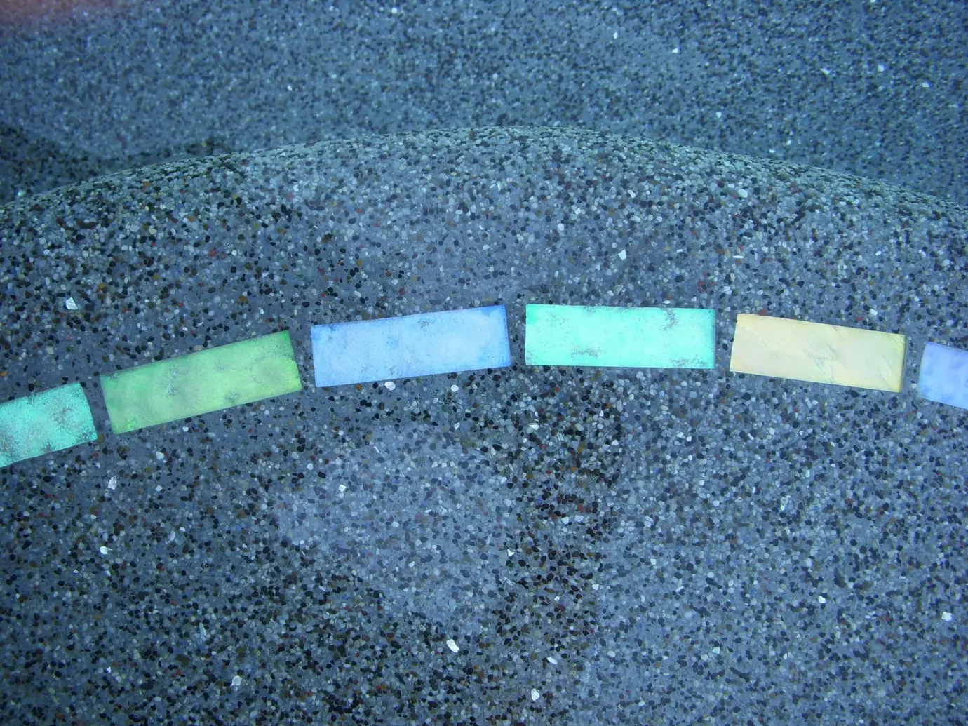 Pebble pool finish with a band of colored glass tiles