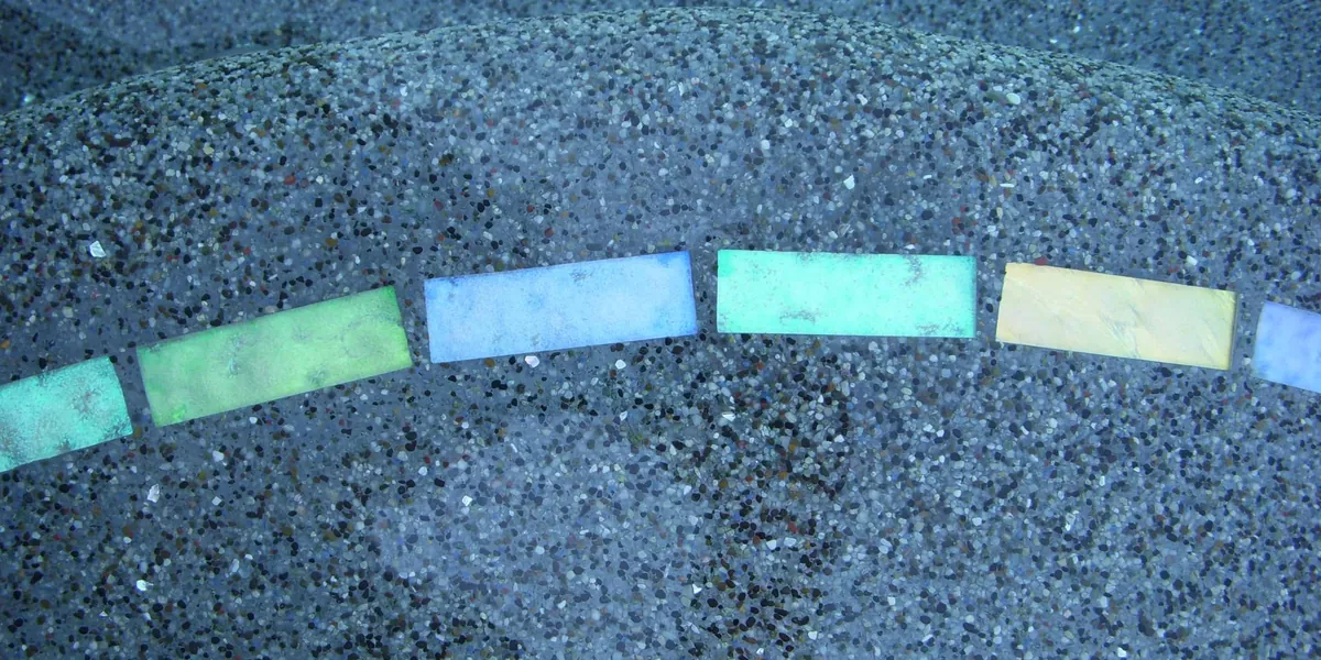 Pebble pool finish with a band of colored glass tiles