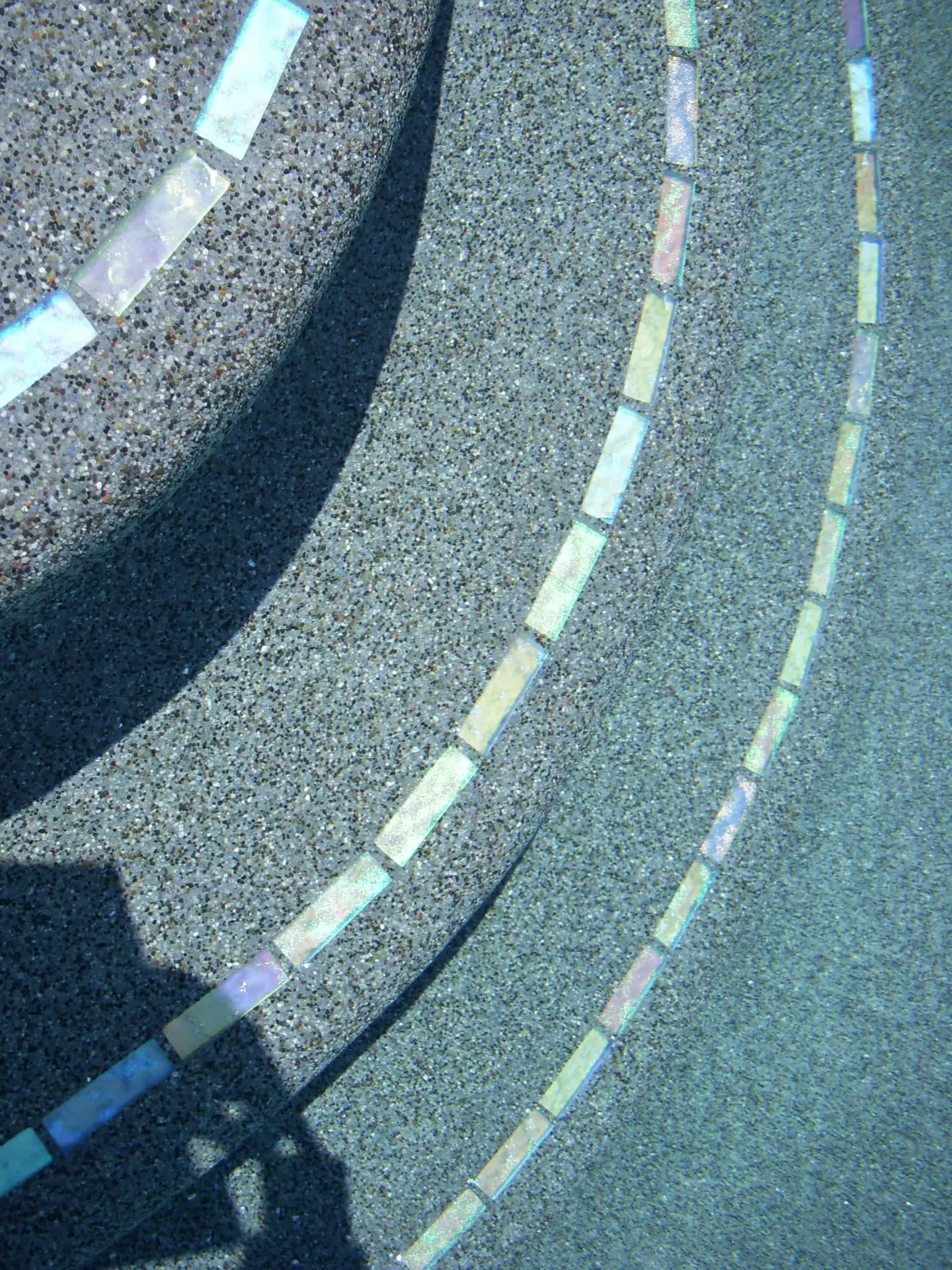 Curved pebble finish steps with glass tile trim lines
