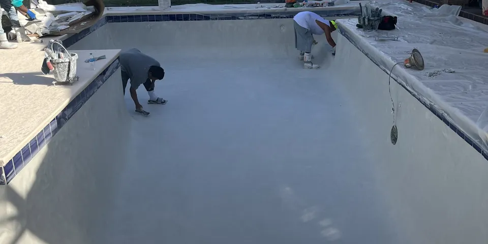 Crew plastering a pool inside a screen enclosure
