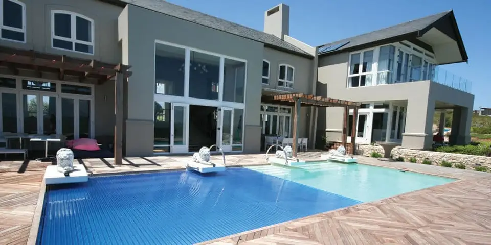 Modern residential pool with blue water, elegant design, and surrounding wooden deck, showcasing a luxurious home setting in Jacksonville Beach, emphasizing pool resurfacing services.