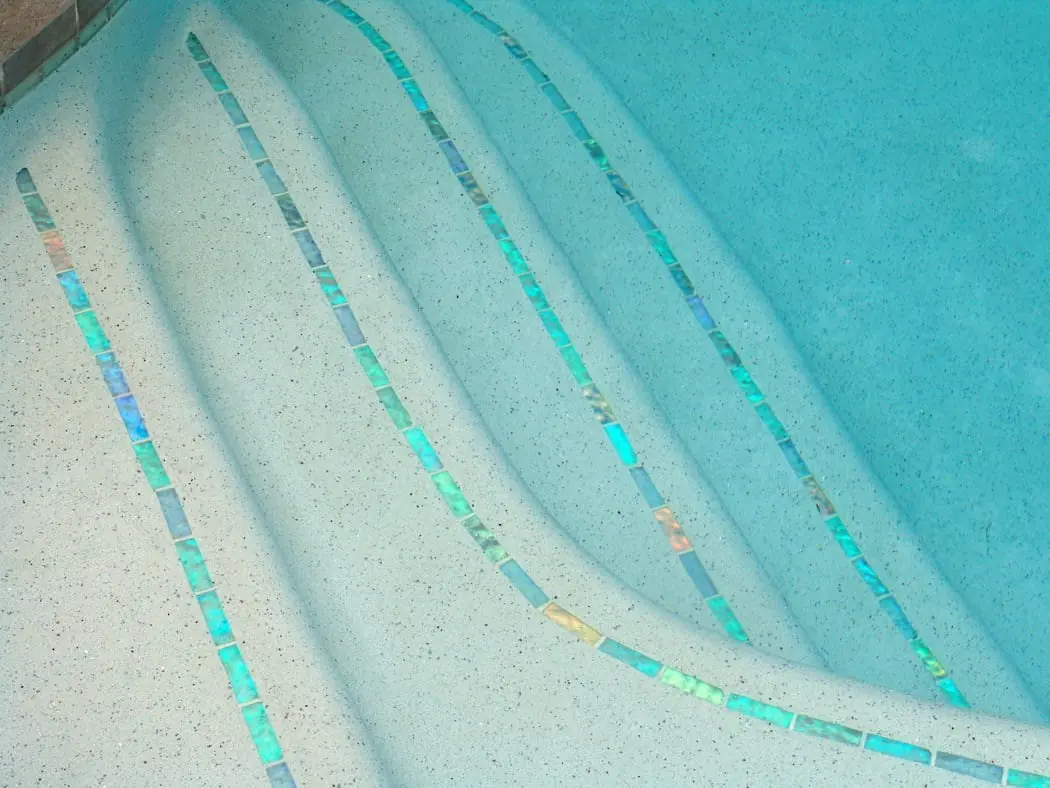 Pool steps with iridescent glass tile lines on each edge