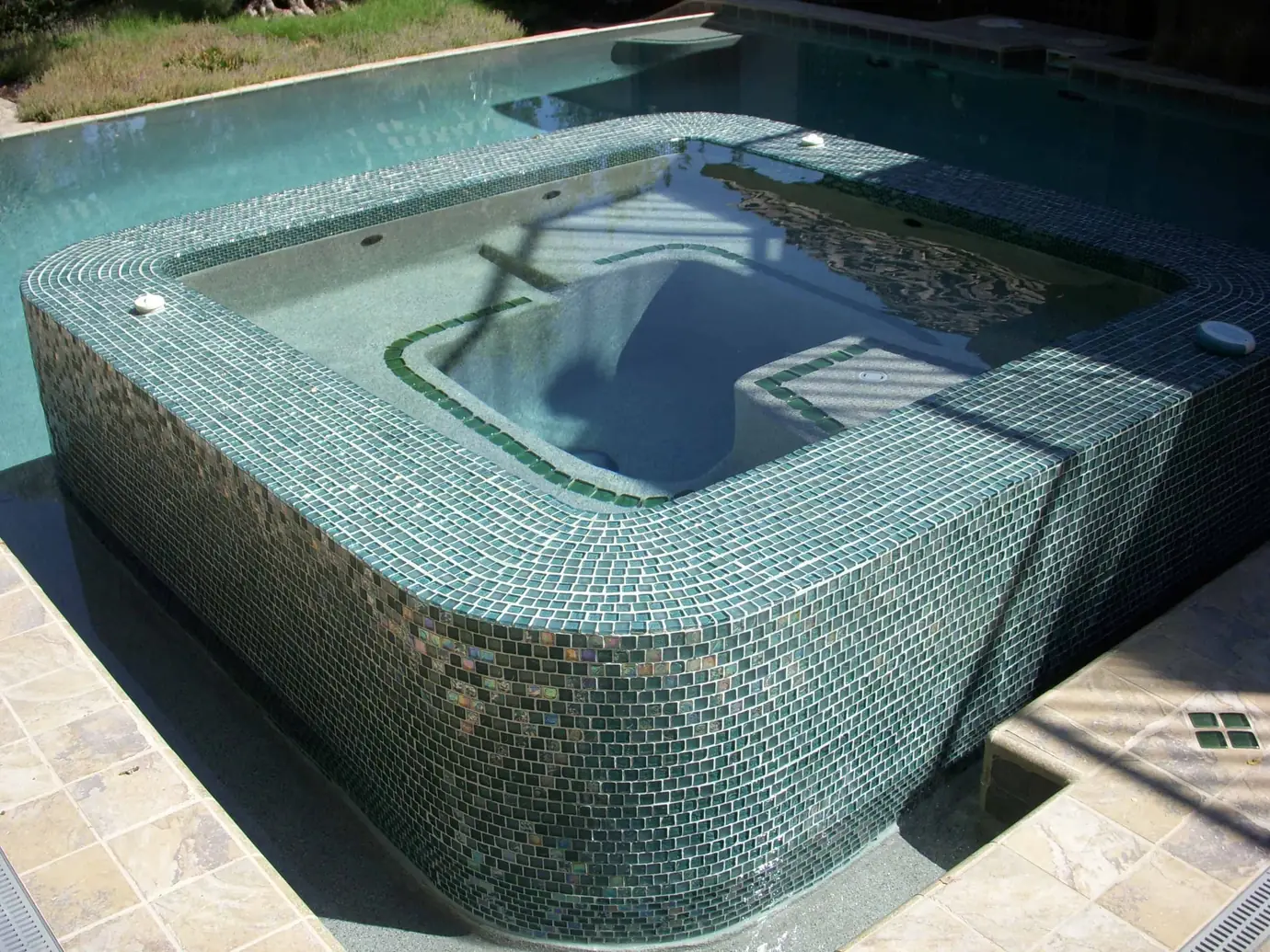 Raised spa covered in iridescent green glass tile