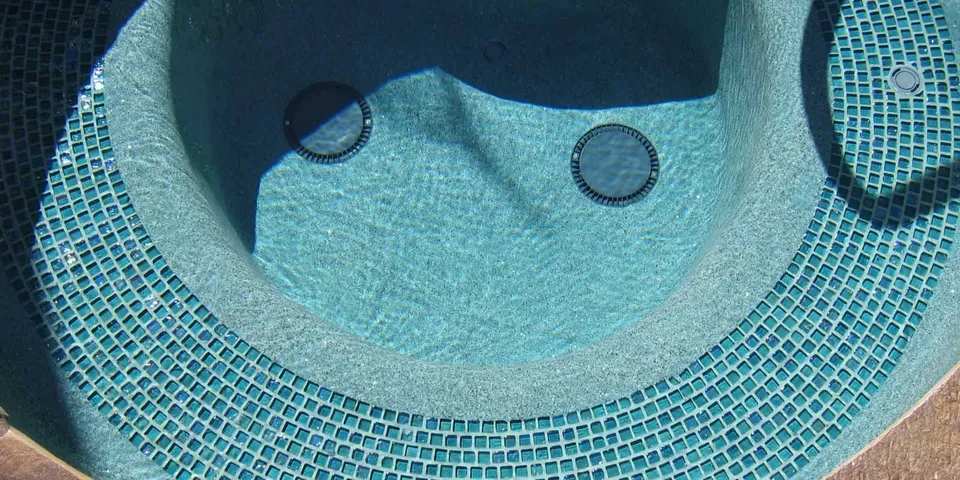 Round spa lined with green glass mosaic tile