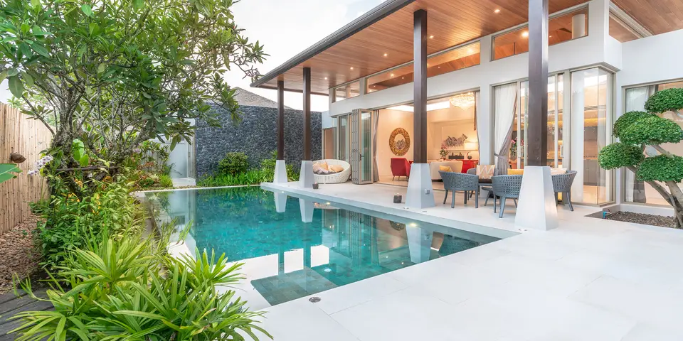 Modern swimming pool surrounded by lush greenery and a stylish patio area, showcasing a serene outdoor living space ideal for relaxation and entertaining, relevant to Classic Marcite's pool resurfacing services in Jacksonville Beach.