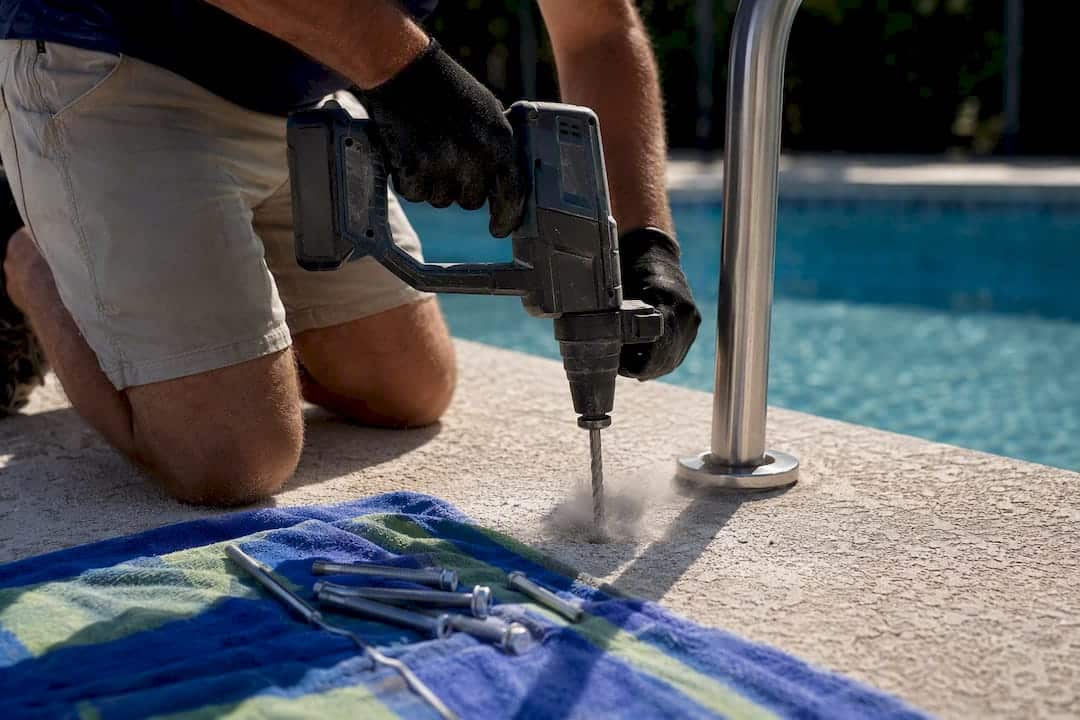 Gloved hands drilling pool deck anchor hole