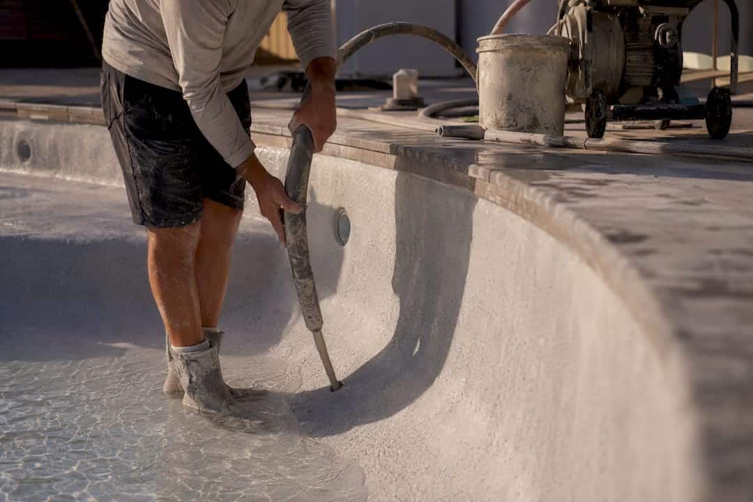 Technician pumping grout under pool shell